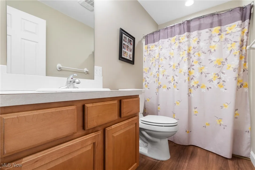 Bathroom featuring wood finished floors, vanity, and curtained shower