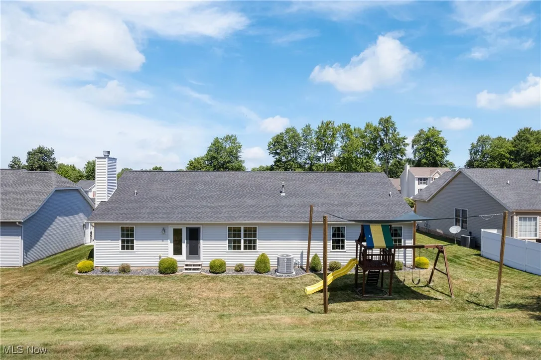 Rear view of property featuring a playground and a shingled roof
