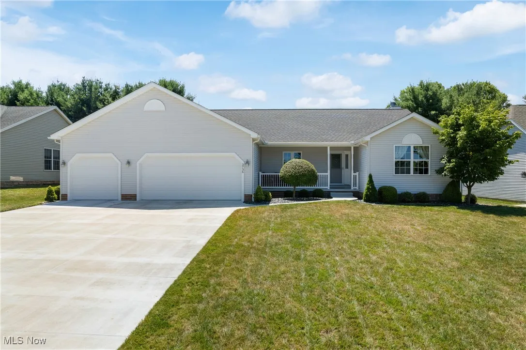 Single story home with a garage, covered porch, roof with shingles, concrete driveway, and a front yard