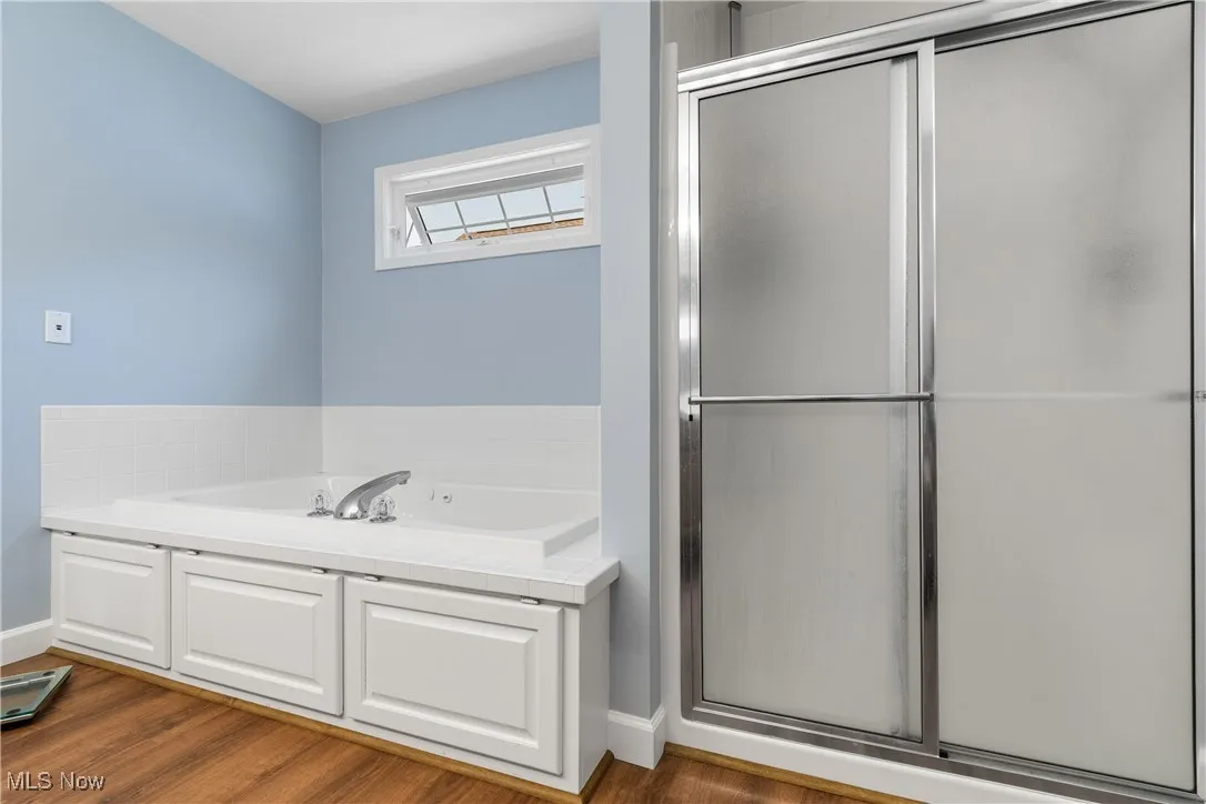 Bathroom with a shower stall, a garden tub, and wood finished floors