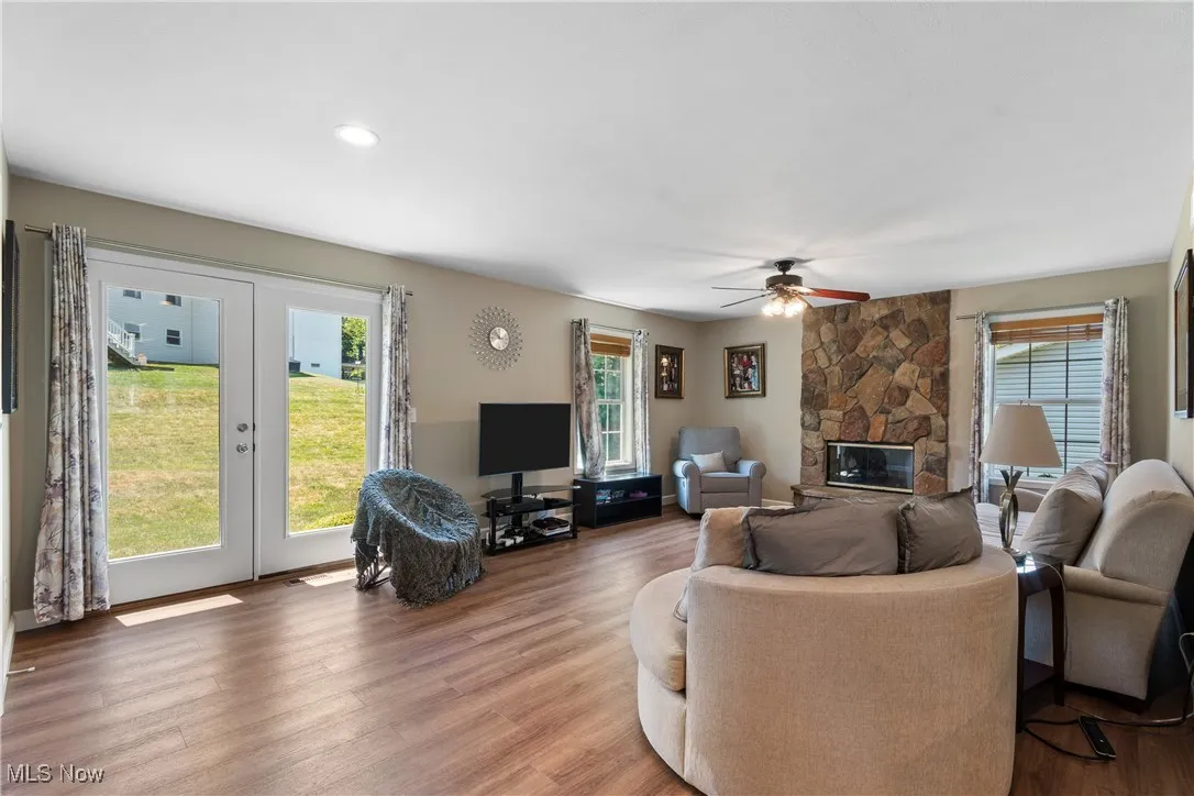 Living area with french doors, light wood-type flooring, ceiling fan, and a fireplace