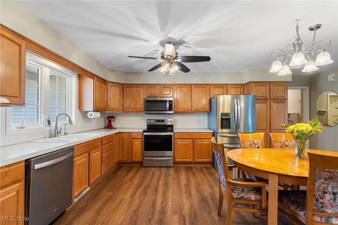 Kitchen with stainless steel appliances, dark wood-style floors, light countertops, and a ceiling fan