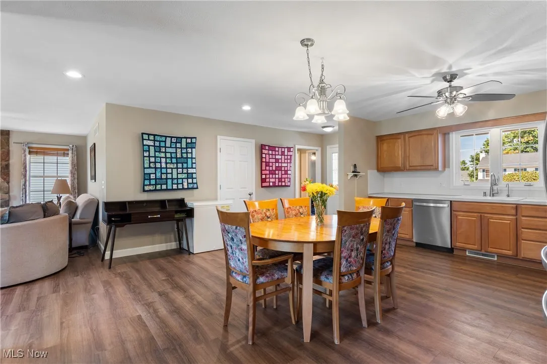 Dining area with dark wood-type flooring, recessed lighting, a ceiling fan, and a chandelier