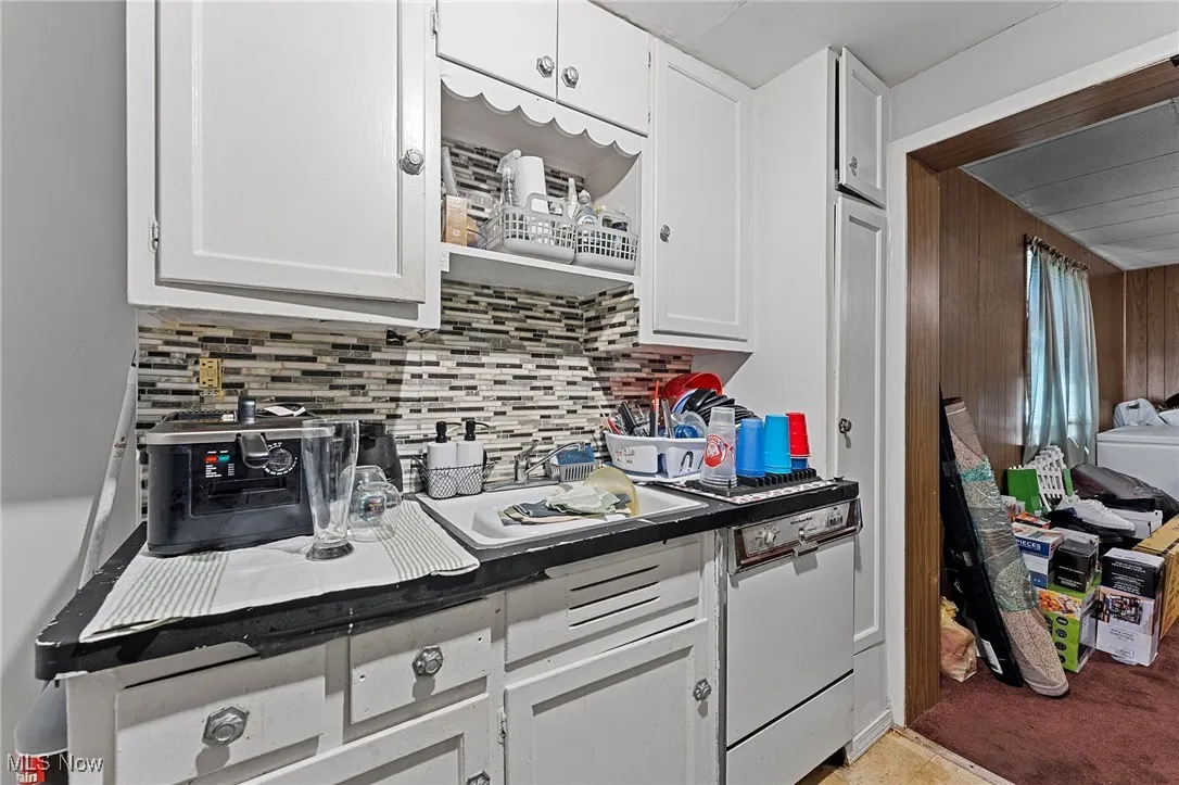 Kitchen featuring backsplash, white cabinets, and dark countertops