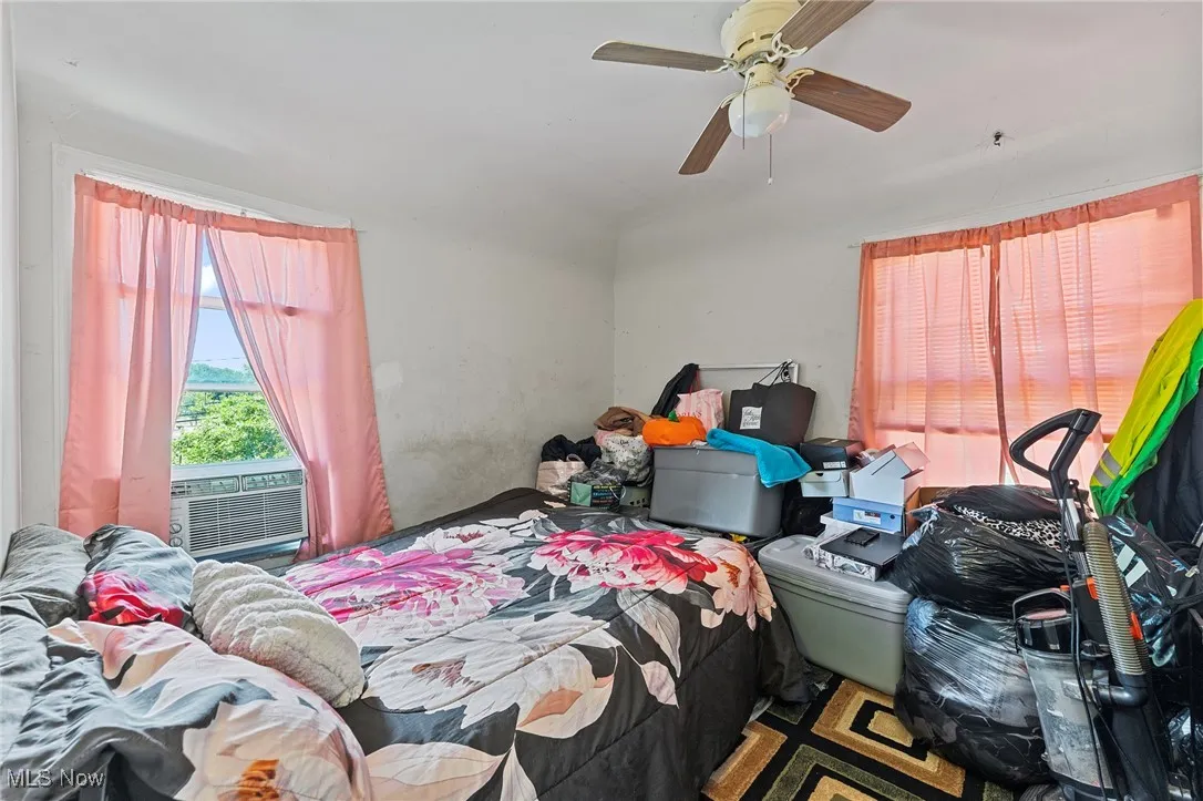 Bedroom featuring multiple windows, a ceiling fan, and cooling unit