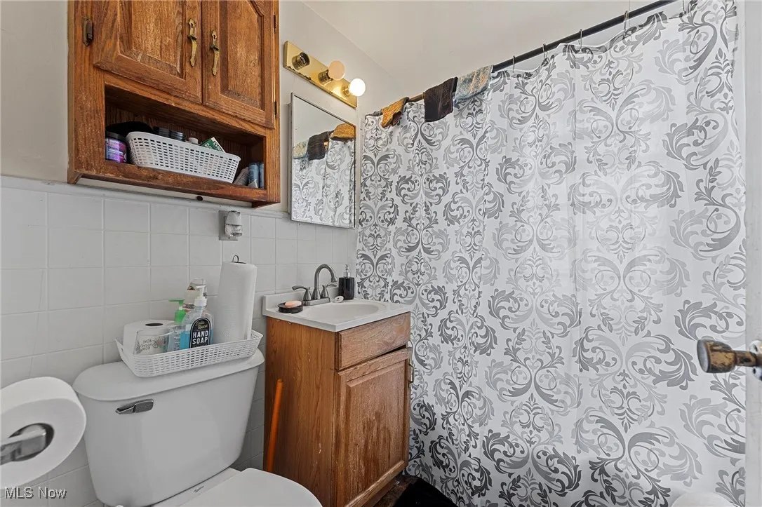 Bathroom featuring tile walls, vanity, and curtained shower