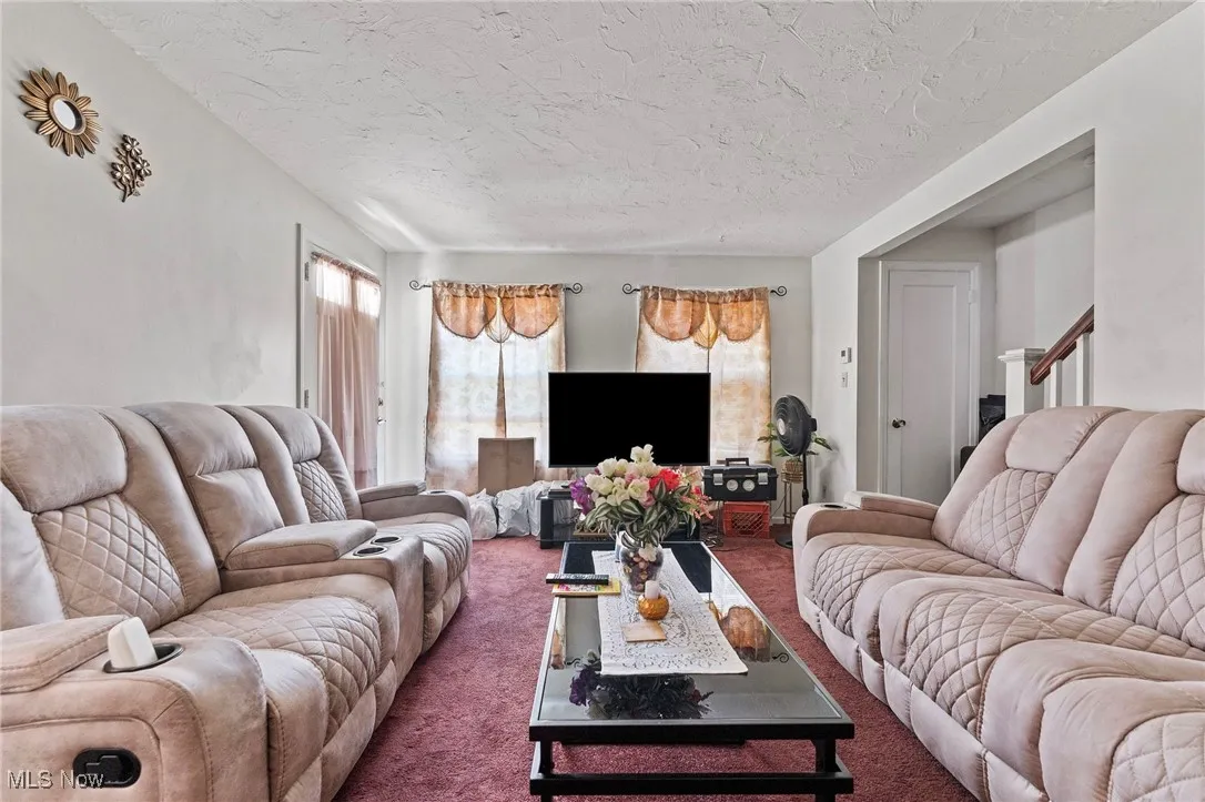 Living room featuring carpet flooring, a textured ceiling, and stairway