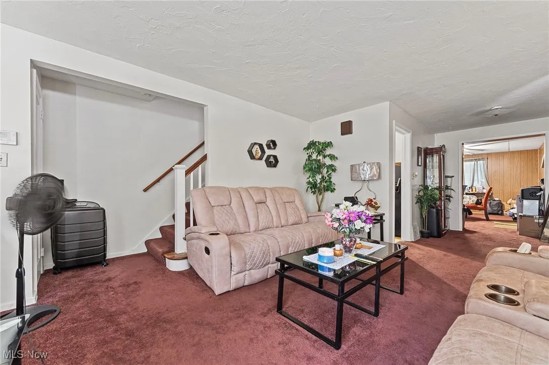 Living room featuring carpet floors, stairs, and a textured ceiling