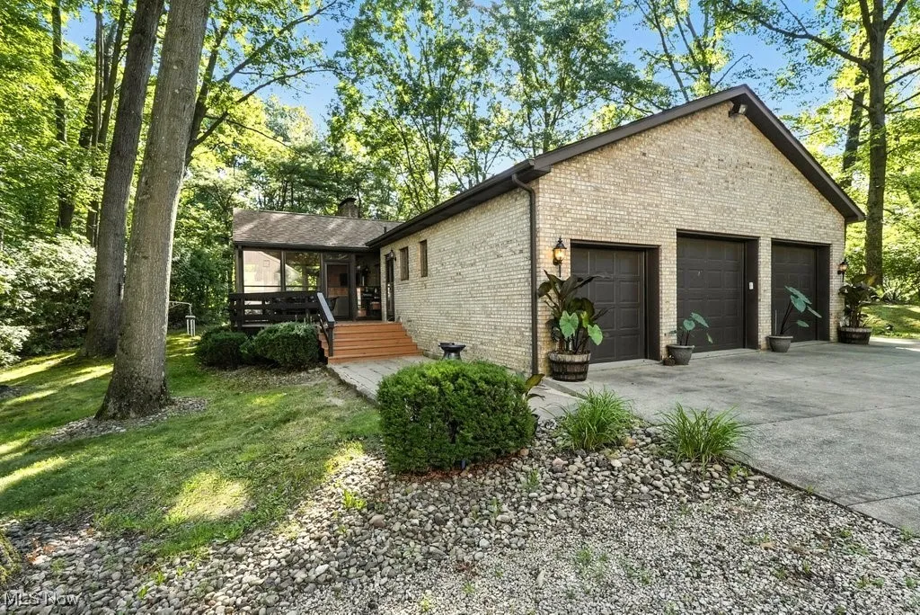 View of side/back of home featuring brick, a chimney, an attached garage, and a wooden deck