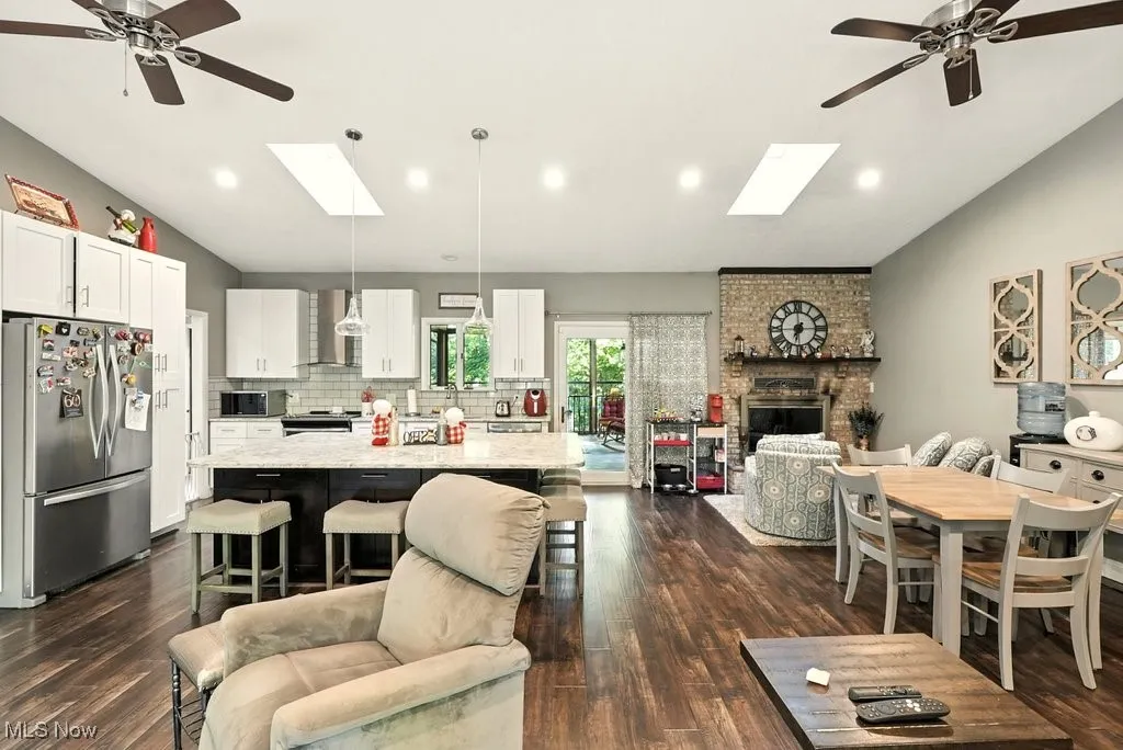 Living room with lofted ceiling, a skylight, ceiling fan, dark wood-type flooring, and recessed lighting