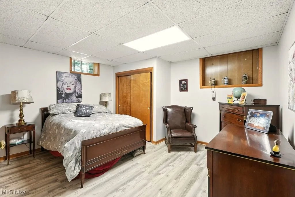Bedroom featuring a drop ceiling, a closet, and light wood-style floors