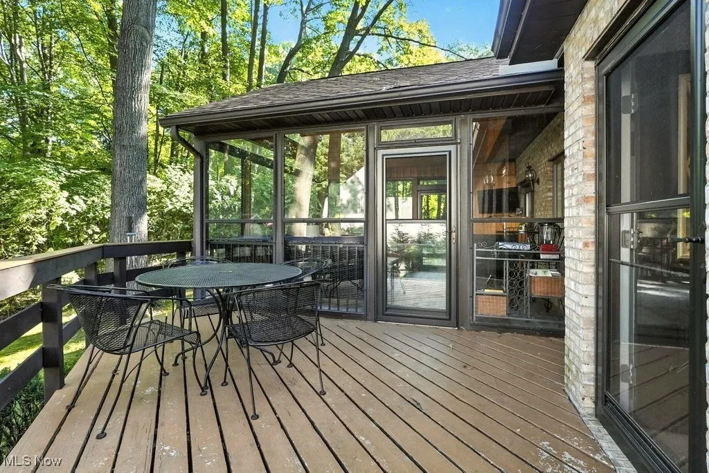 Wooden deck with a sunroom and outdoor dining area