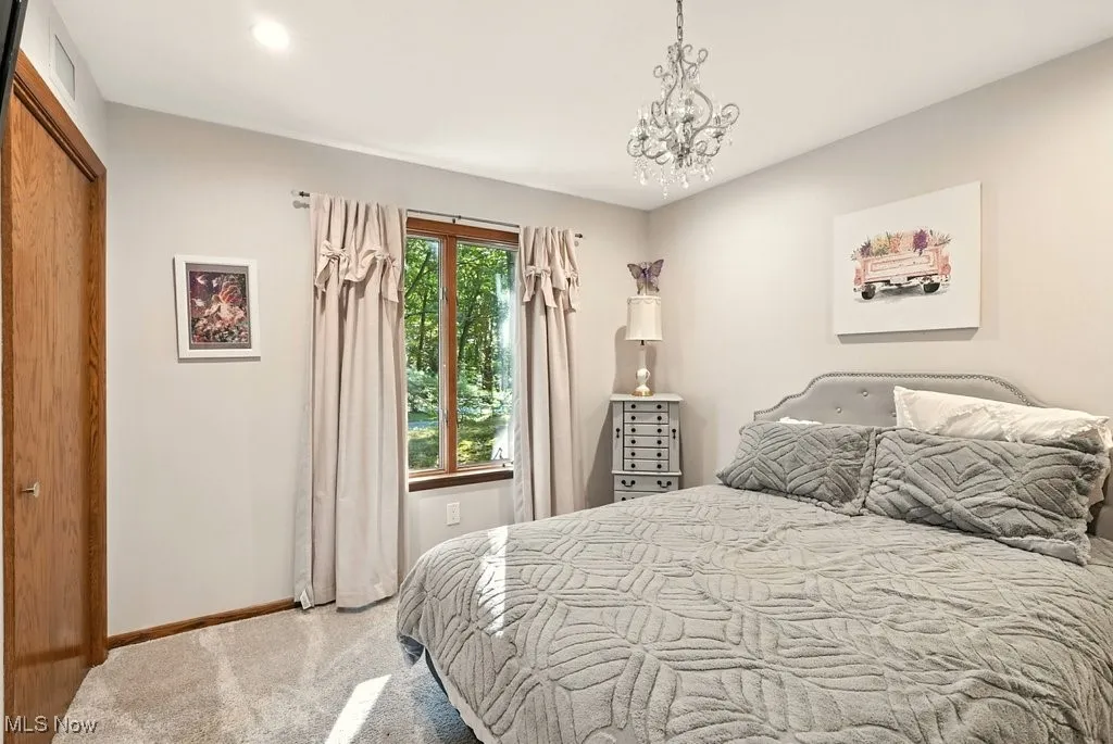 Bedroom with light carpet and a chandelier