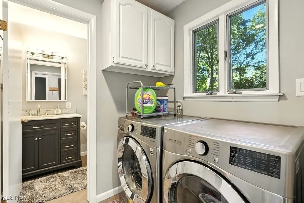 Washroom featuring washing machine and dryer, cabinet space, and wood finished floors