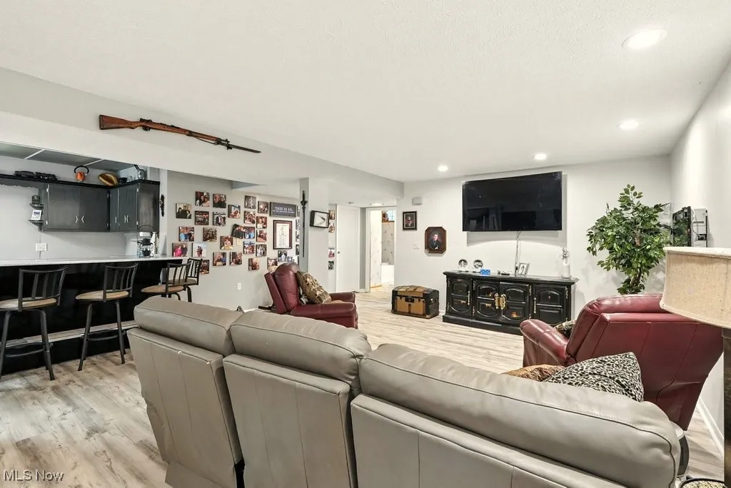 Living room with light wood finished floors, wet bar, and recessed lighting