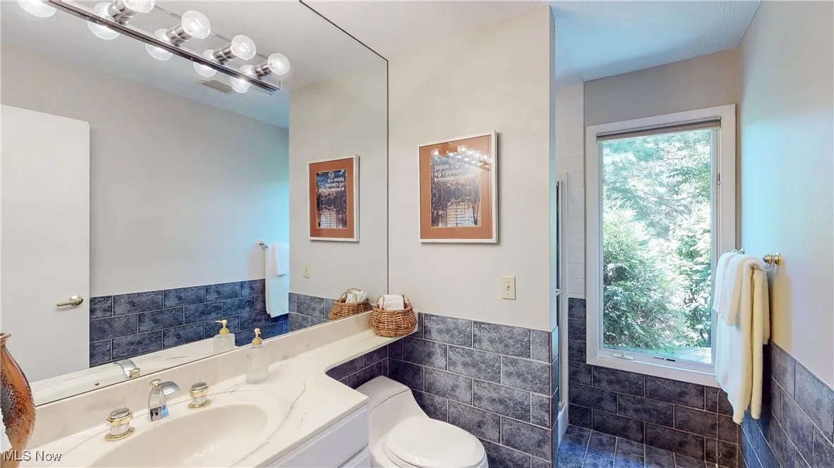 Bathroom featuring tile walls, wainscoting, and vanity