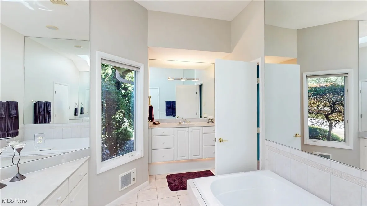 Bathroom with a bath, vanity, and tile patterned flooring