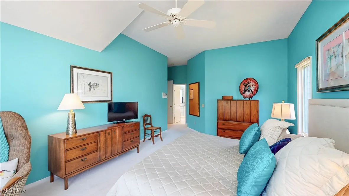 Bedroom with light carpet, ceiling fan, and lofted ceiling