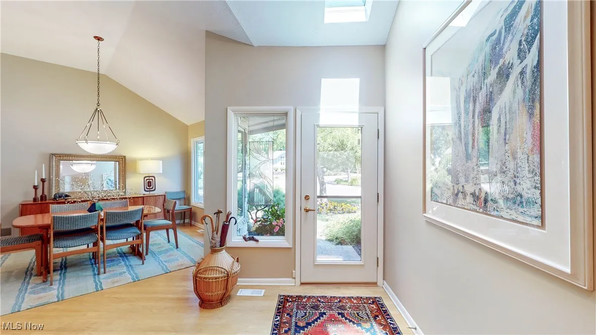 Doorway featuring plenty of natural light, wood finished floors, and lofted ceiling