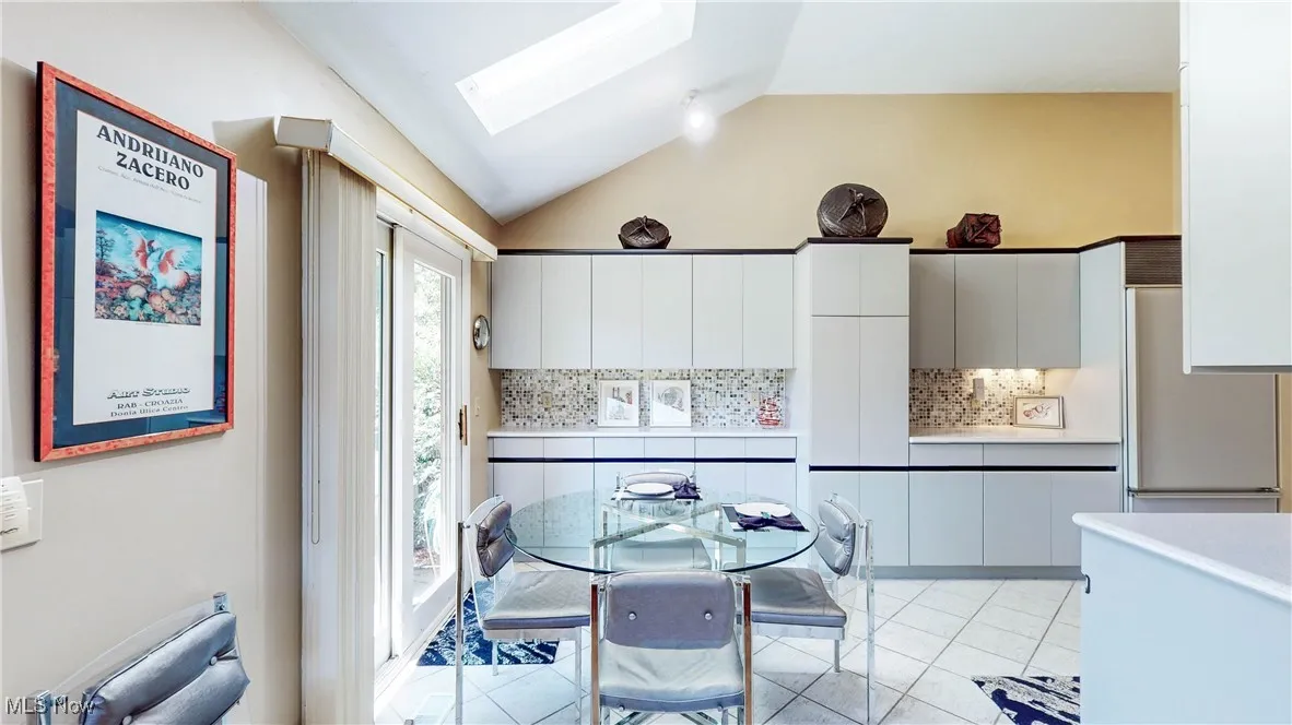 Dining area featuring lofted ceiling, a skylight, and light tile patterned floors
