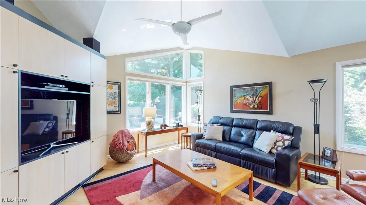 Living room featuring lofted ceiling, light wood-style flooring, and ceiling fan