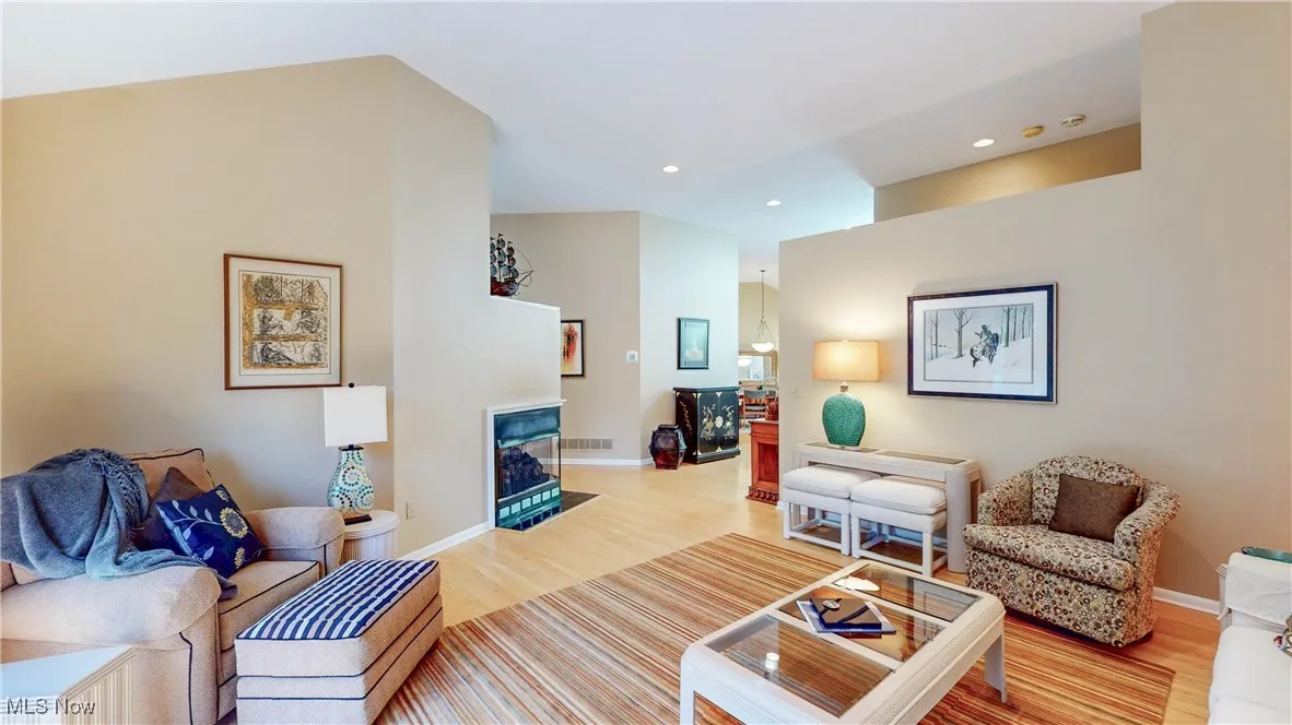 Living area with wood finished floors, a fireplace with flush hearth, and recessed lighting