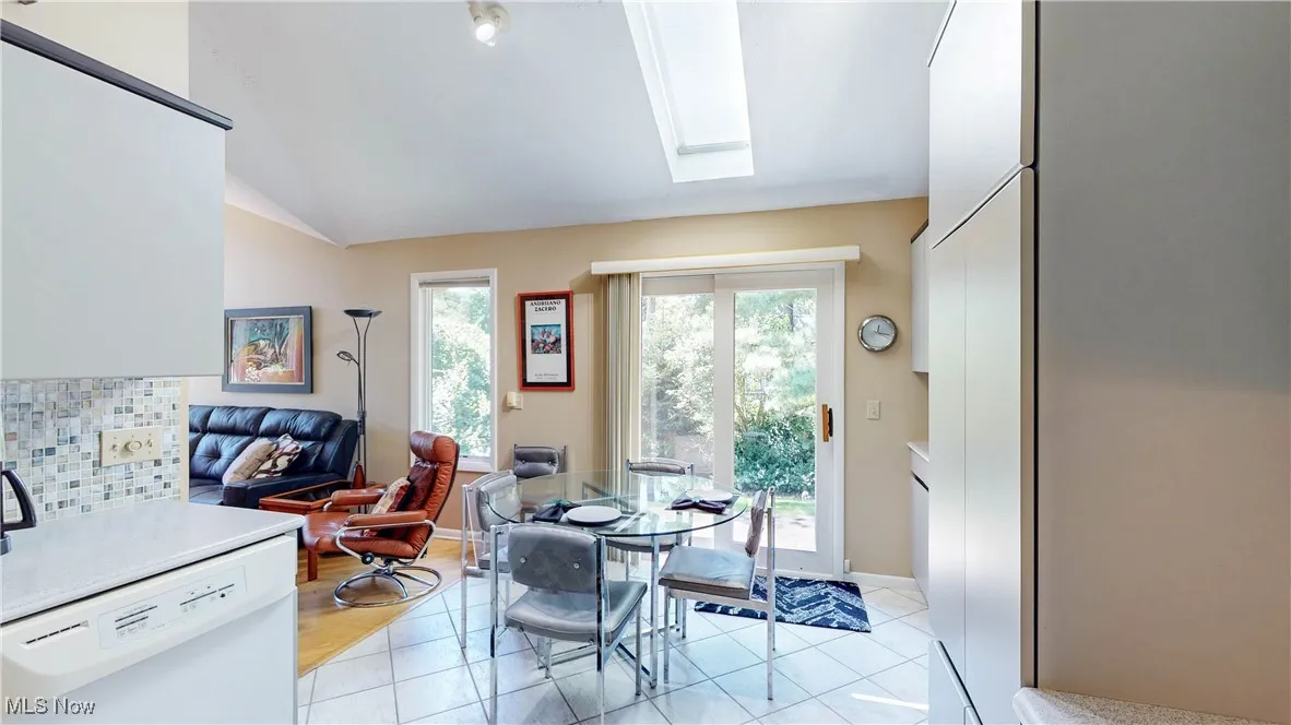 Dining room with a skylight, light tile patterned flooring, and lofted ceiling