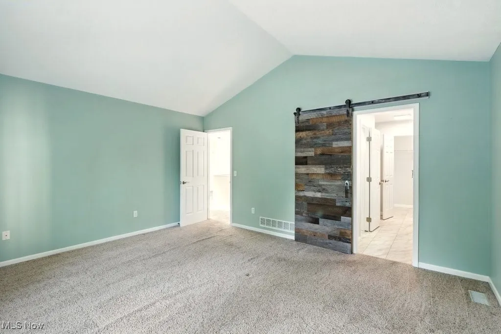 Unfurnished bedroom featuring vaulted ceiling and carpet floors