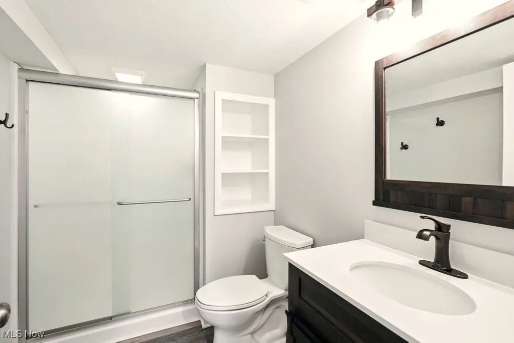 Full bathroom with a stall shower, vanity, wood finished floors, and built in features