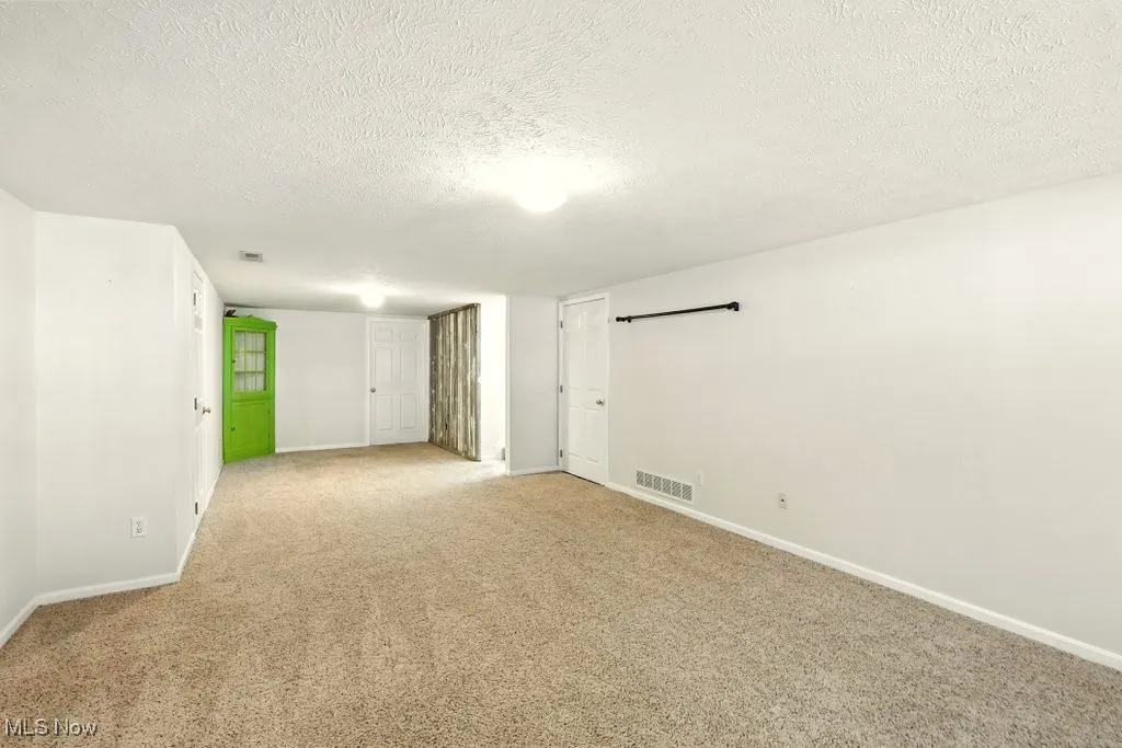 Spare room featuring a textured ceiling and light colored carpet