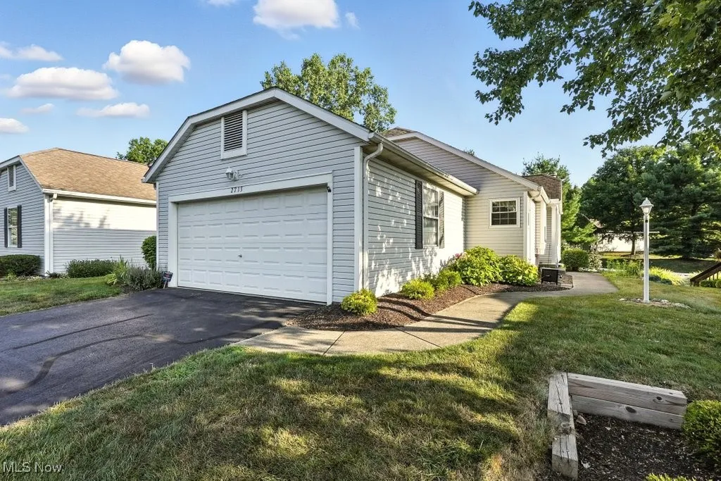 View of side of property with driveway, an attached garage, and a lawn