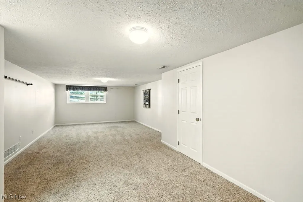 Empty room with a textured ceiling and carpet