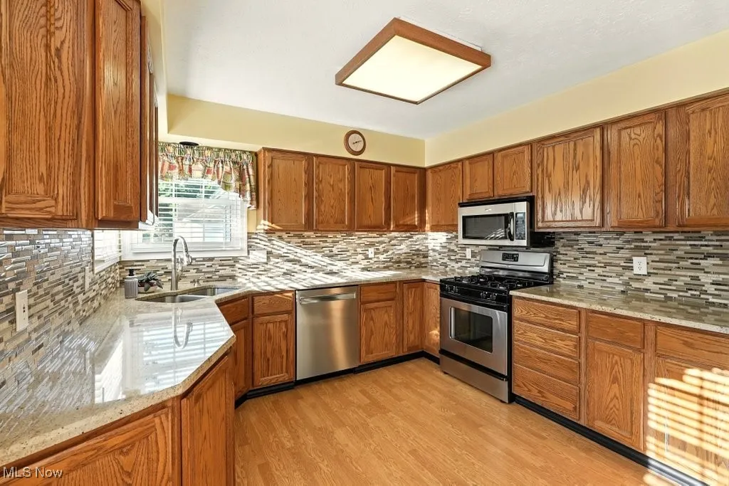 Kitchen featuring brown cabinets, appliances with stainless steel finishes, and backsplash