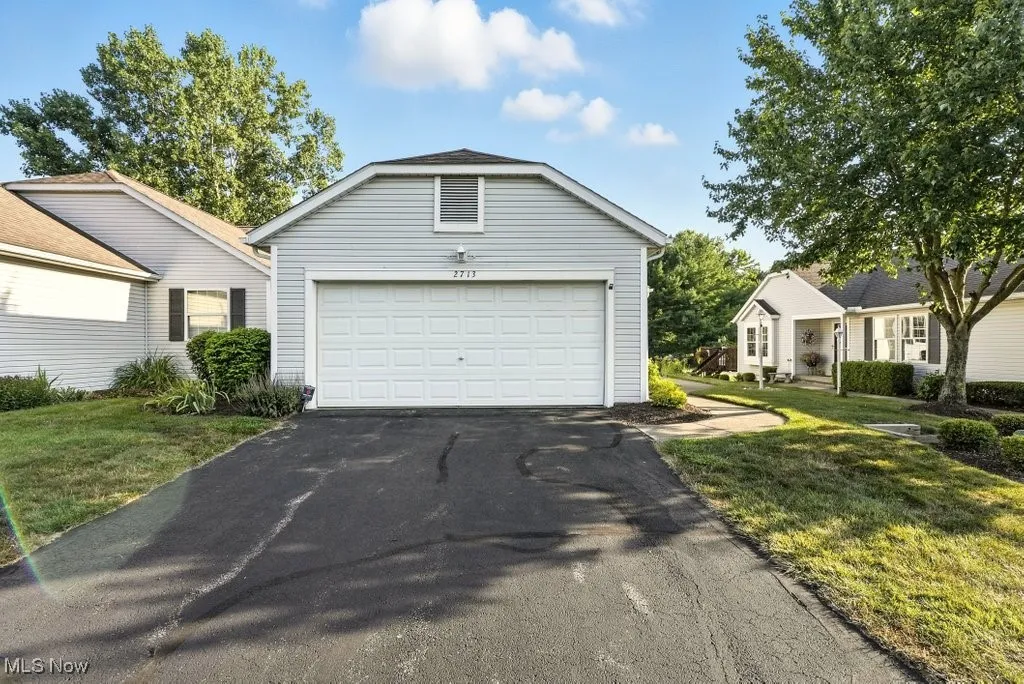 View of front of property featuring a garage, driveway, and a front yard