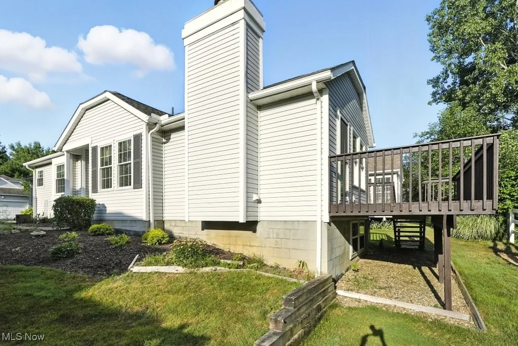 View of home's exterior featuring a wooden deck, a chimney, and a lawn