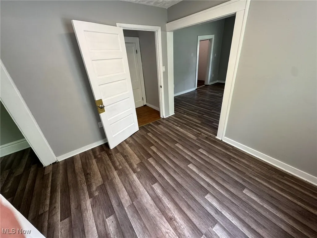 Unfurnished office in between living and dining rooms featuring dark wood-style LVP floors, baseboards, and attached half-bath.