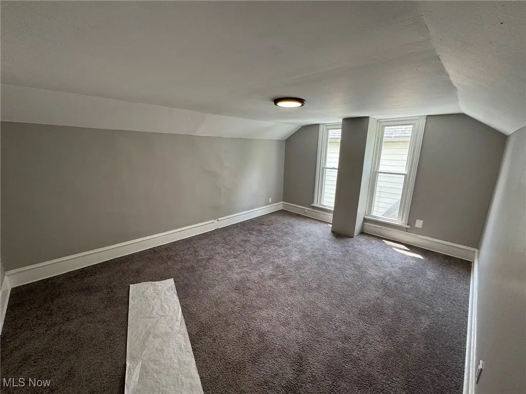 Bedroom 1 featuring vaulted ceiling and carpet floors