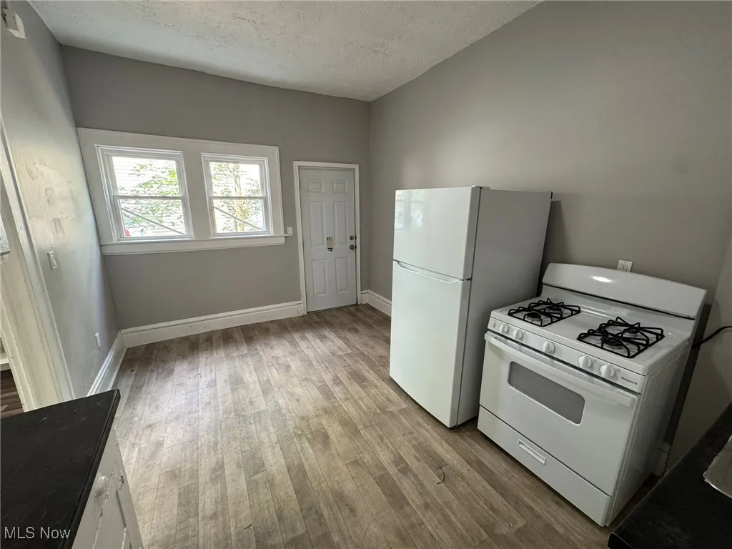 Kitchen featuring white fridge and gas stove, wood LVP finished floors, and a textured ceiling