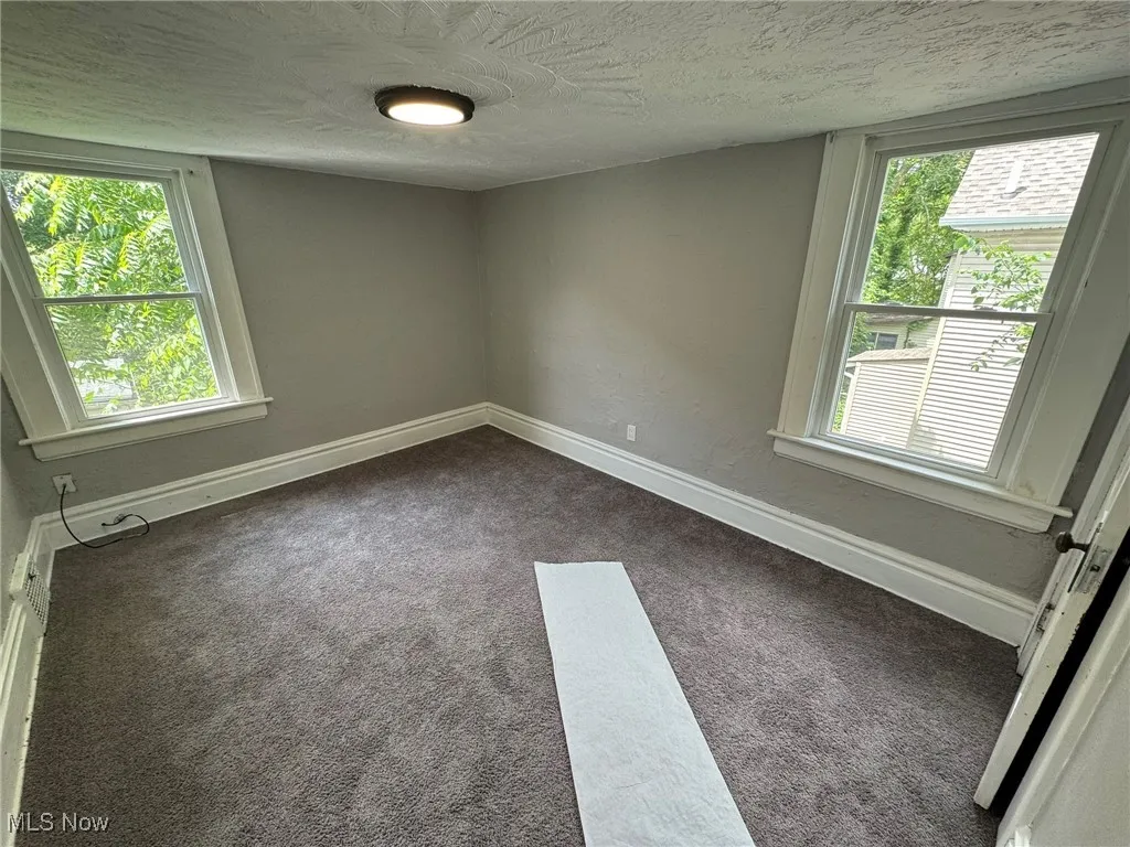 Bedroom 2 with dark colored carpet, healthy amount of natural light, and a textured ceiling