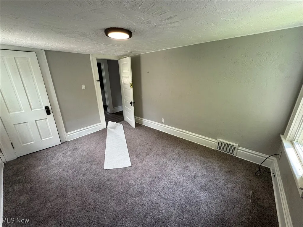 Bedroom 3 featuring dark carpet and a textured ceiling