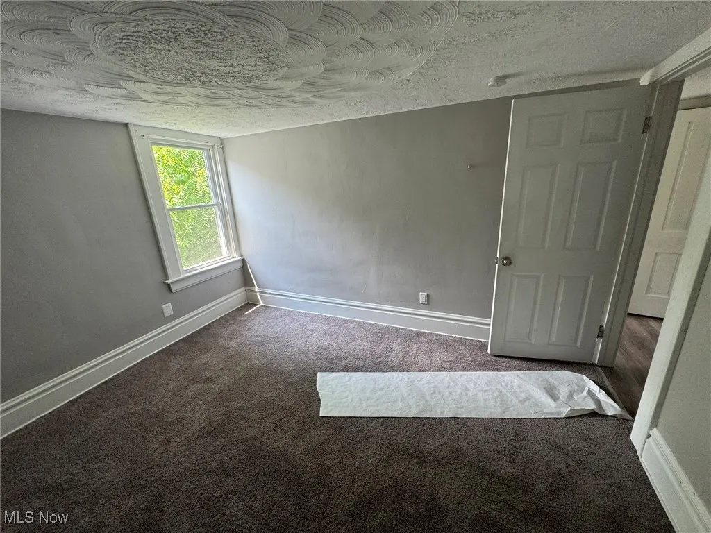 Bedroom 1 with dark colored carpet and a textured ceiling