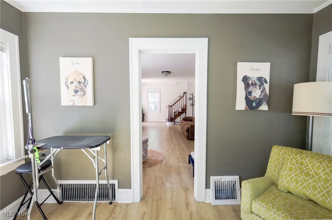 Living area featuring wood finished floors, ornamental molding, and stairs