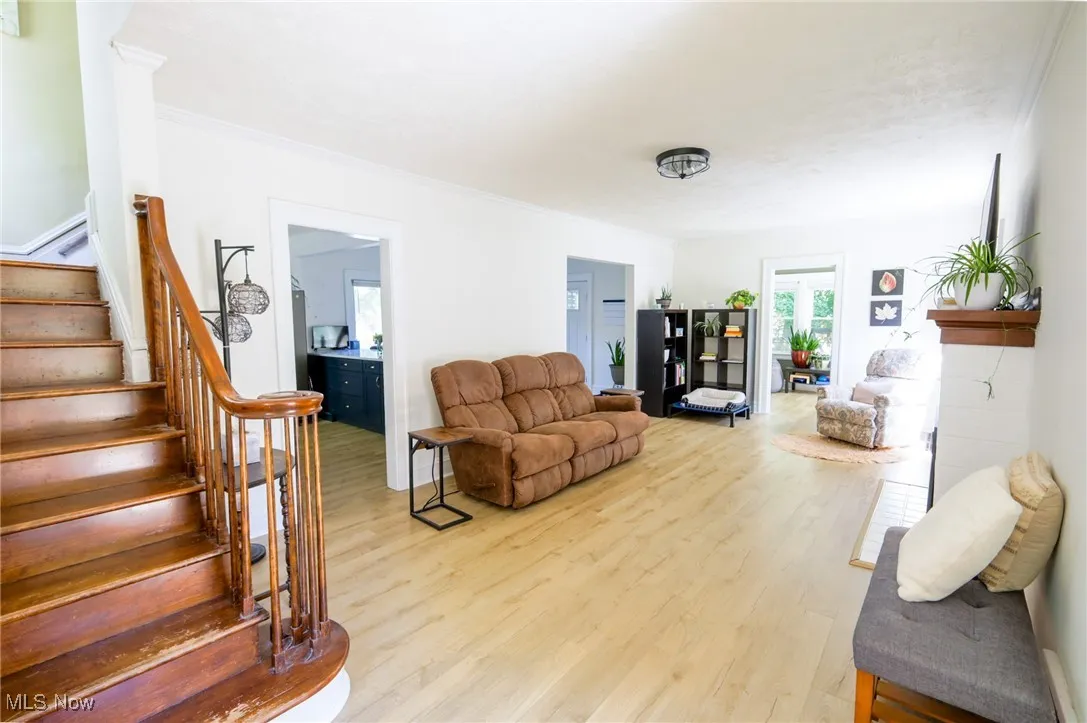 Living area with stairway, light wood-type flooring, and crown molding