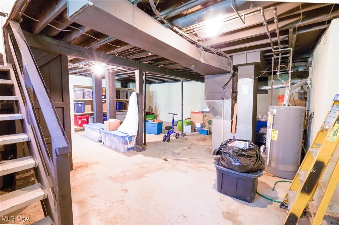 Unfinished below grade area with water heater, heating unit, and stairs