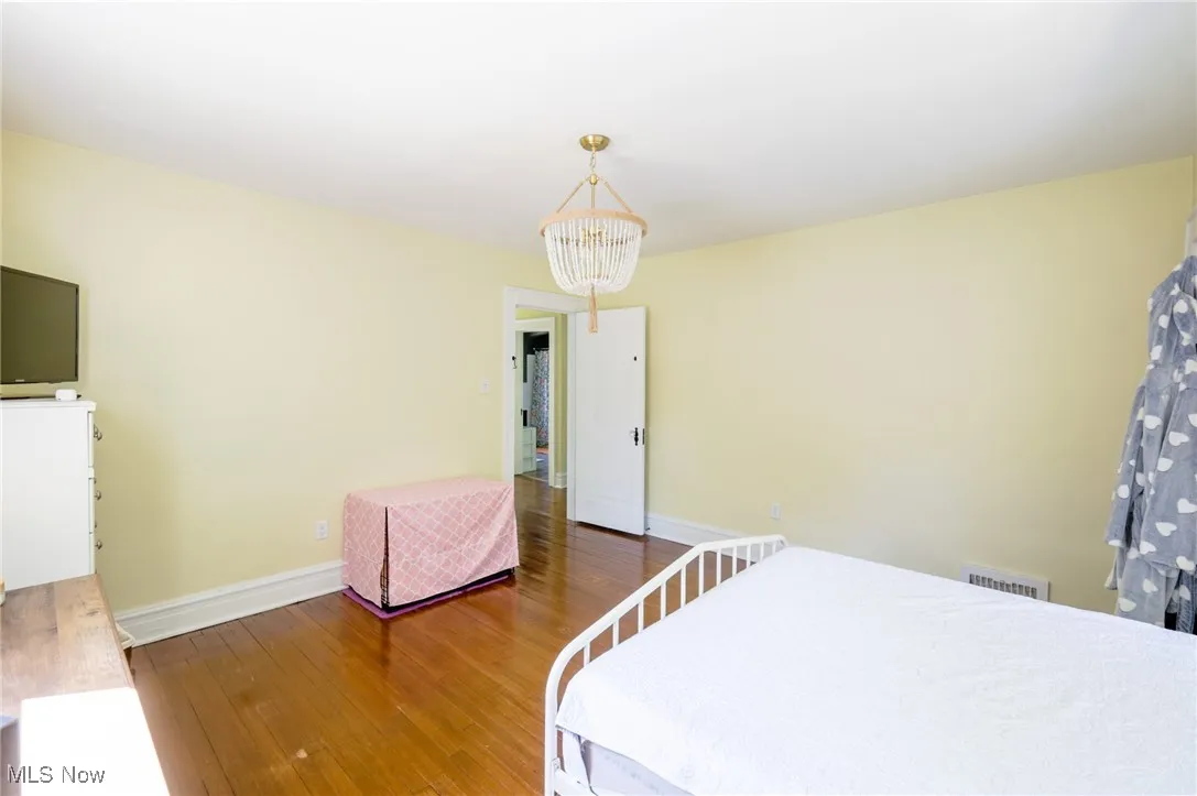 Bedroom with wood finished floors and a chandelier