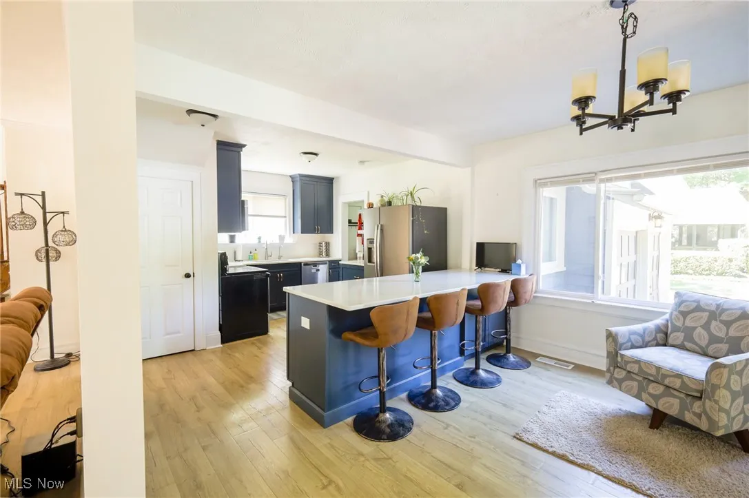 Kitchen with a breakfast bar area, light wood finished floors, light countertops, and appliances with stainless steel finishes