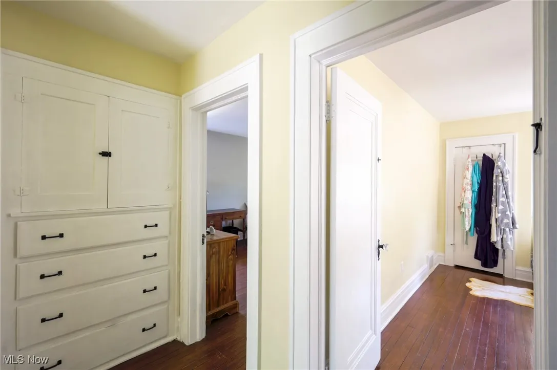 Corridor featuring dark wood-style flooring and baseboards