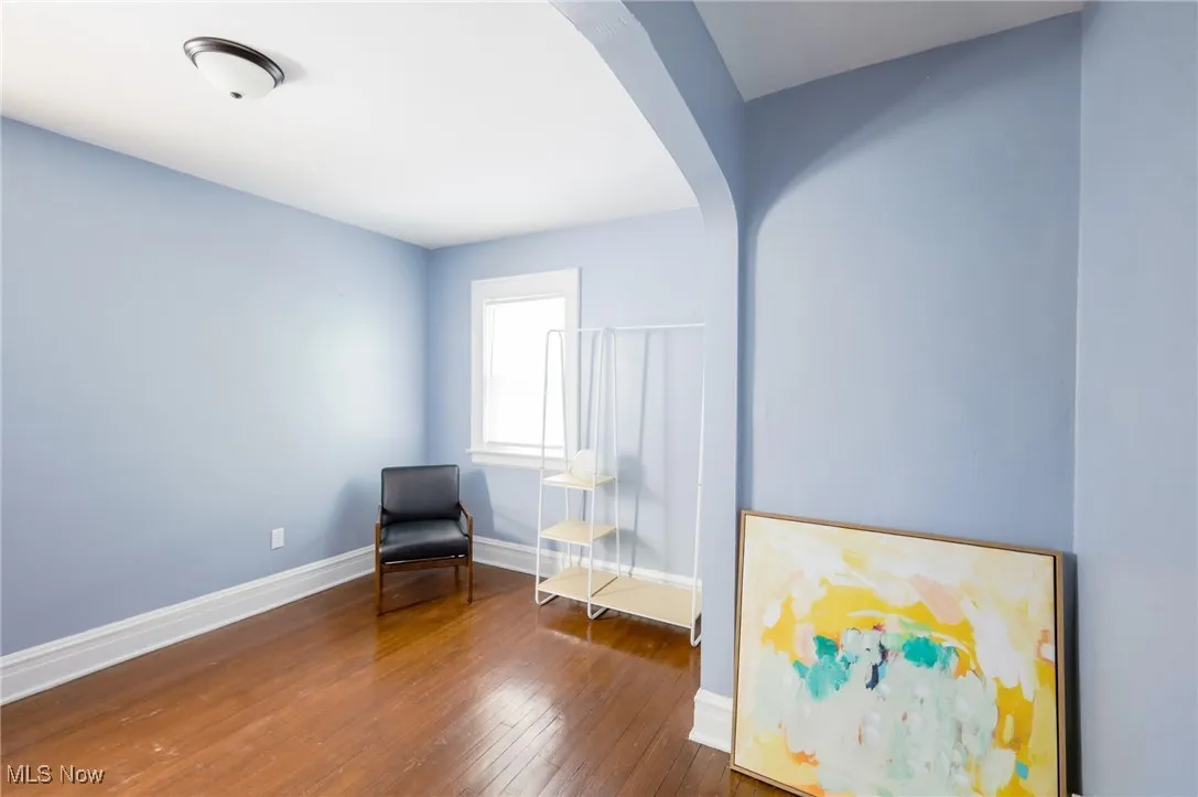 Unfurnished room with arched walkways and wood-type flooring