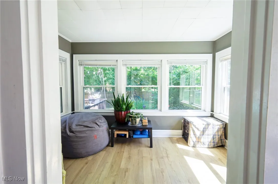 Sunroom / solarium with wood finished floors and ornamental molding