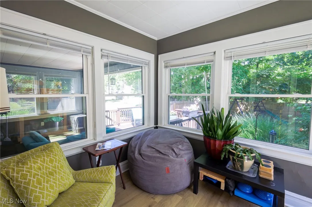 Sunroom featuring wood finished floors and crown molding